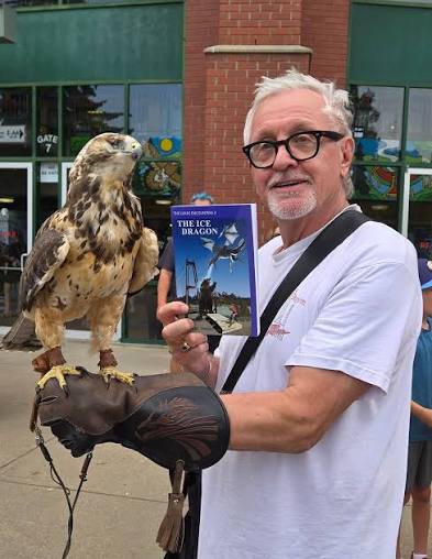 Stuart Adams holding a copy of Lukas and the Ice Dragon, with a hawk